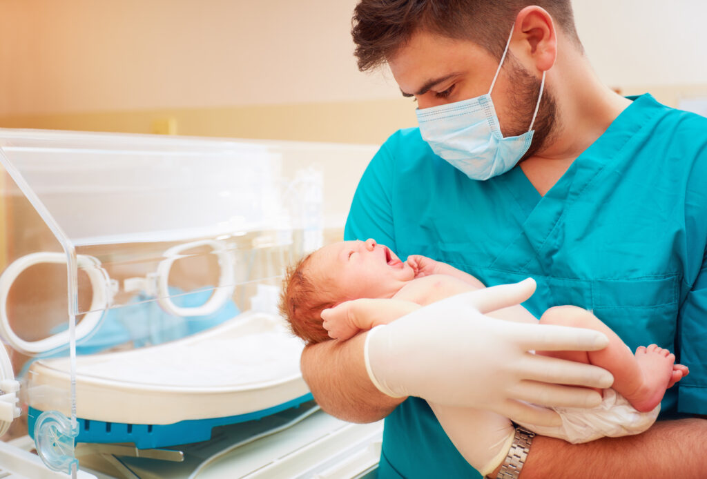 Young,Adult,Man,Holding,A,Newborn,Baby,In,Hospital